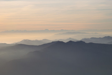 silhouettes of mountains in the middle of the fog  and clouds at sunset