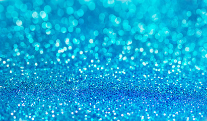 Blue defocused glitter background with copy space. Holiday texture. Wallpaper. Glitter light spots on blue background, defocused