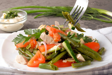 Spring salad of chicken breast, mushrooms, black-eyed peas, cucumbers, tomatoes and onions on a white plate. Concept of healthy food.