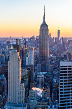 Naklejki New York City - USA. View to Lower Manhattan downtown skyline with famous Empire State Building and One World Center and skyscrapers at sunset.
