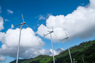 Three wind turbines on the back are green mountains and beautiful sky.