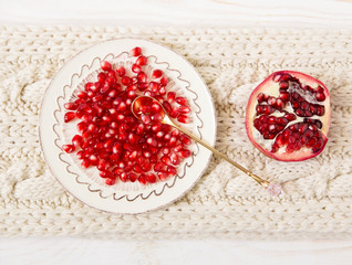 seeds of pomegranate on the plate.golden spoon.knitted background.top view