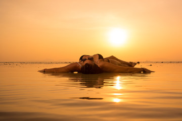 Fototapeta premium Silhouette of a young and fit woman on the beach at sunset