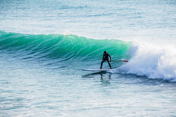 Surfer ride on stand up paddle board on ocean waves. Stand up paddle boarding in ocean