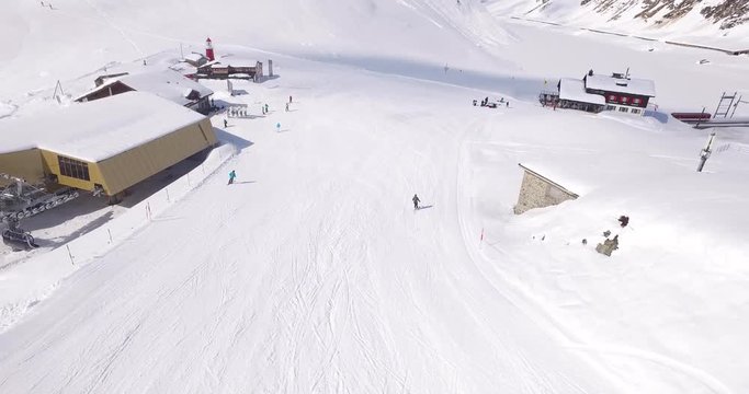 Aerial following skiers down the snow covered slopes in Andermatt in winter