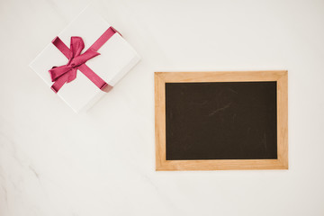 top view of blank blackboard in frame with gift box isolated on white