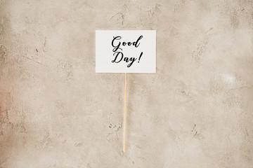 top view of good day lettering on placard on concrete surface