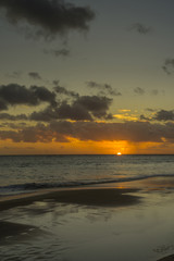 Naklejka na ściany i meble Sunset on the Atlantic coast with dark clouds and little waves