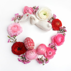 Easter eggs and ranunculus flowers frame on white background. Flat lay