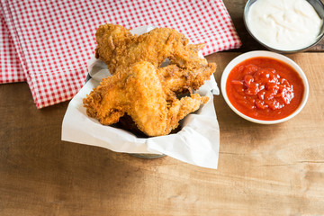 deep fried chicken wings served with ketchup and mayonnaise on old wooden table, top view.