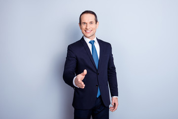 Obraz na płótnie Canvas Cheerful financier, positive economist, corporate, responsible politic man in formalwear with tie offering hand for shaking, having a deal, standing over gray background