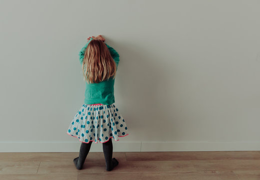 Little girl standing up against a wall