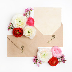 Obraz na płótnie Canvas Flat lay shot of letter and eco paper envelope on white background. Wedding invitation cards or love letter with ranunculus flowers. Valentine's day or other holiday concept. Top view