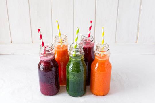 Detox drinks in bottles: fresh smoothies from vegetables: beetroot, carrot, spinach, cucumber and apple on white background