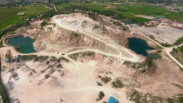 aerial drone shot : fly over a mountain stone quarry with dump trucks loaded with stone