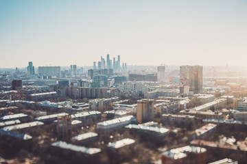 Fototapeta premium True tilt-shift view of autumn or spring cityscape with skyscrapers and residential houses, with focus on the middle zone of the image; background and foreground are blurred and have strong bokeh