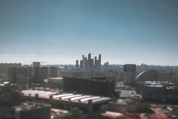 True tilt-shift view from the high point of the cityscape on a sunny day with the city center and the group of business and residential skyscrapers in the background and strong bokeh in the foreground