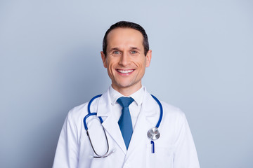 Fototapeta premium Close up portrait of cheerful qualified professional clever smart successful glad friendly surgeon with toothy beaming shiny smile with blue stethoscope on shoulders isolated on gray background