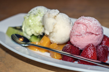 Appetizing dessert: 3 balls of ice cream with fruit on a white plate