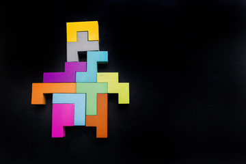 Obraz premium robot silhouette wooden blocks on black background. human Geometric shapes in different colors. Concept of creative, logical thinking or problem solving. Flat lay. Top view. Copy space.