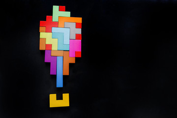 exclamation mark silhouette wooden blocks on black background. Geometric shapes in different colors. Concept of creative, logical thinking or problem solving. Flat lay. Top view. Copy space.