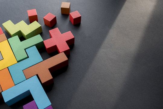 Different colorful shapes wooden blocks on black background, flat lay. Geometric shapes in different colors, top view. Concept of creative, logical thinking or problem solving. Copy space.