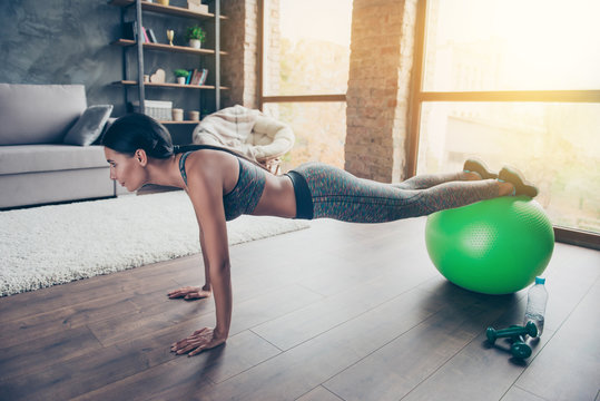 Side profile view photo of active attractive charming beautiful enduring muscular slim skinny strong woman dressed in clothes for training using fit ball for doing push-ups in reflection