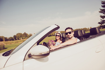 Married family, friendship, trip, relax, chill, escape, speed ride. Well dressed brunet driver in eyewear, femenine girlish lady in cap enjoy her nice pink purple gift present in arm