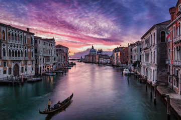 Fototapeta na wymiar Sonnenaufgang über dem Kanal Grande in Venedig, Italien, mit vorbeifahrender Gondel 