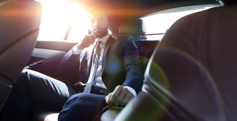 businessman talking on the phone while sitting in the back seat 