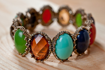 Bracelet of bright colored stones on a wooden background
