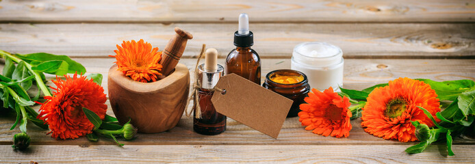 Calendula aromatherapy. Essential oil and cosmetics, blank tag, banner. Wooden table background