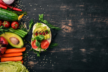 Burger, avocado sandwich, cherry tomatoes and lettuce leaves. On a wooden background. Top view. Copy space.