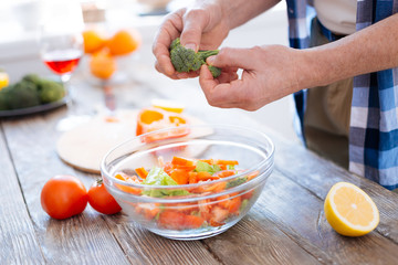Vitamin fuel. Selective focus of tender male hands tearing broccoli while preparing salad and consuming vegetables
