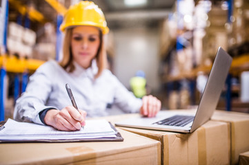 Young warehouse worker with laptop working.