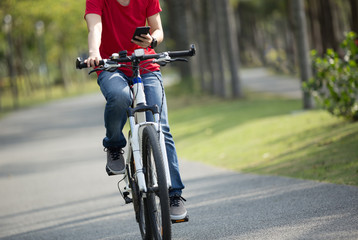 Naklejka premium cyclist use cellphone while riding bike in tropical park