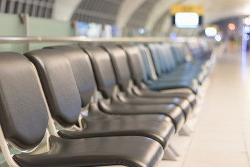 Airport blur background for air transportation travel concept with blurry bench seats for traveller or tourist on corridor in waiting area of airport departure flight or bus terminal building interior