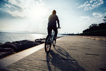cyclist riding bike in the sunrise coast path