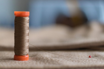 An ocher / brown fuze standing over a brown ocher cloth. A pin with red head in the blurred background