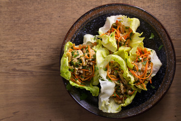 Lettuce wraps with chicken, carrot, peanuts and scallion. Stuffed iceberg lettuce leaves with...