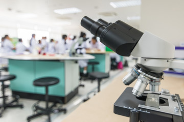 Fototapeta na wymiar Biology or chemistry science class study with microscope and blur background of school student group learning in blurry lab classroom with teacher for education concept