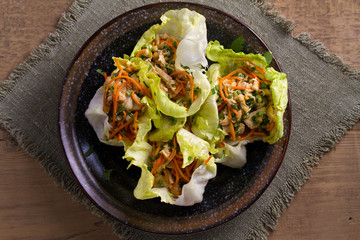 Lettuce wraps with chicken, carrot, peanuts and scallion. Stuffed iceberg lettuce leaves with chicken. View from above, top