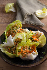 Lettuce wraps with chicken, carrot, peanuts and scallion. Stuffed iceberg lettuce leaves with chicken