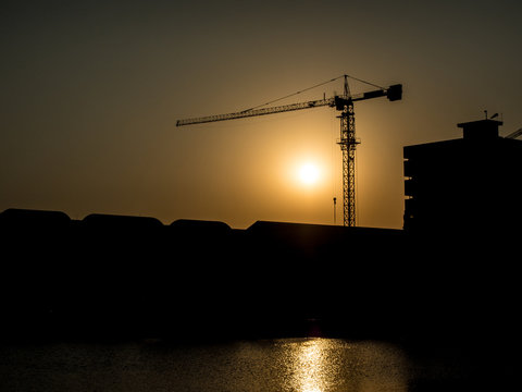 Silhouette image -  Derrick for the construction of the building at sunset.