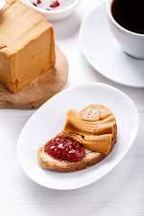 Norwegian brunost on white table. Breakfast with Scandinavian brown cheese, bread and coffee.