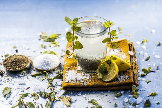 Indian popular summer drink SABJA NIMBUPANI/SWEET BASIL DRINK WITH LEMON and sugar in dark Gothic colors on a wooden surface.;