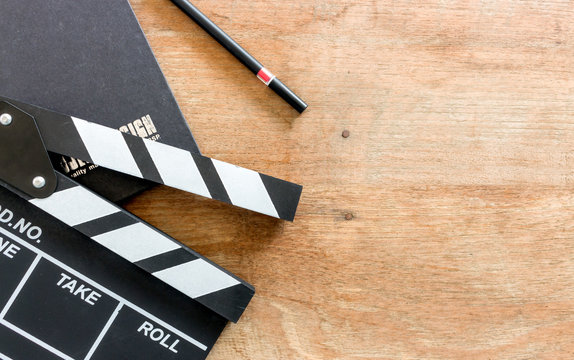 film director's desk. clapboard and black book on wood table with soft-focus and over light in the background