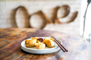 Dumping on a white plate and on a light wooden table. Chinese food. Food sticks. On the back of a blurry background, a white brick pad is covered with an word - love. Side view with copy space. 
