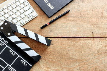 film director's desk. clapboard and black book on wood table with soft-focus and over light in the background