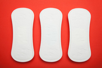 Three sanitary napkins on a red background.